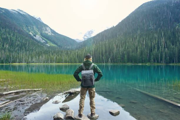 istock Active tourist with backpack standing at mountain lake and wood background 1488453194