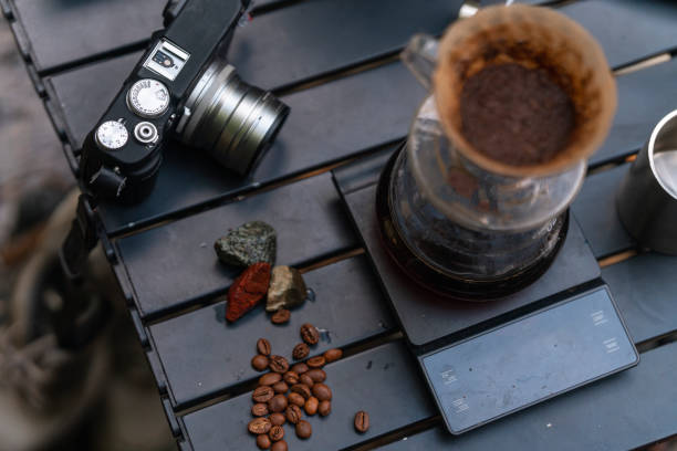 a selective focus on coffee brewer and coffee pot with camera, grinder, stove in the backgrounda selective focus on coffee brewer and coffee beans with camera, grinder, stove in the background stock photo
