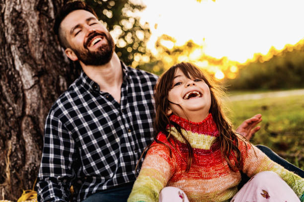 istock Father and elementary age daughter laughing together enjoying time outside in nature in fall 1488455889