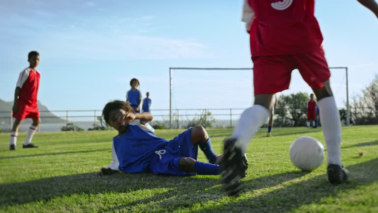 Football, sport and running with children playing on a field during a competitive team game in summer. Exercise, soccer and fitness with a group of kids outdoor together for a match on a grass pitch