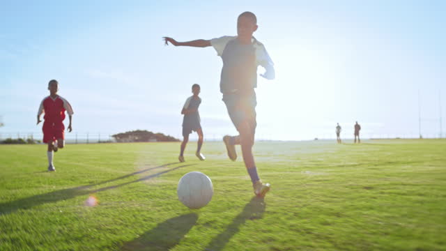 Sports, running and soccer by children with ball at field for practice, training or match. Kids, fitness and friends or football club having fun, kick and free, energy or workout, tackle or exercise