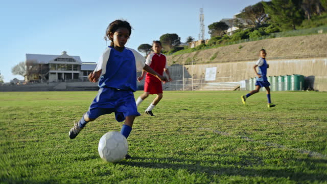 Fitness, kids and team playing football at a match, tournament or training on an outdoor pitch. Sports, children and soccer players practicing for a game or competition on a grass field at a stadium.