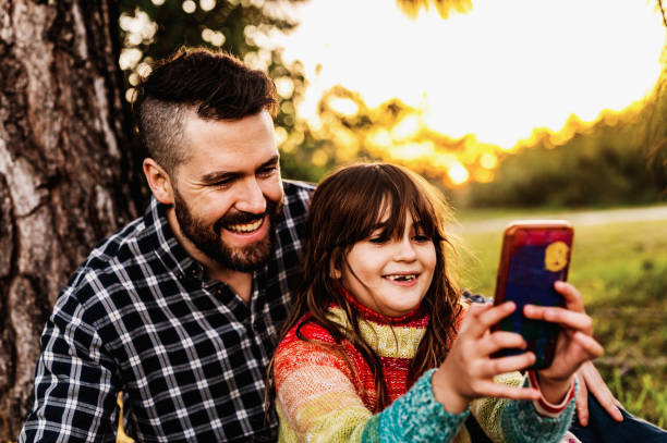 istock Father and elementary age daughter taking a selfie on a phone together enjoying time outside in nature in fall 1488463174