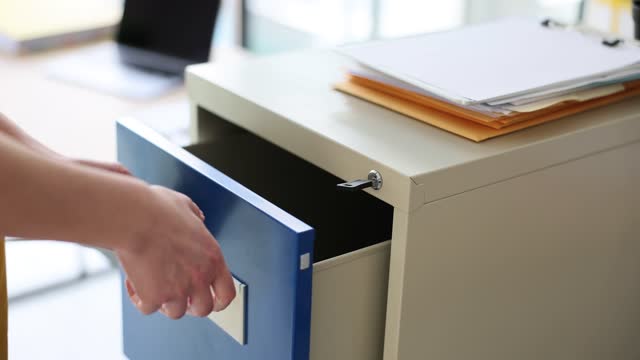 Woman hand opens metal box in office with key