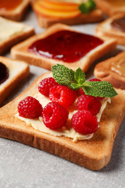 istock Tasty toast with butter, raspberry and mint on light grey table, closeup 1488464895