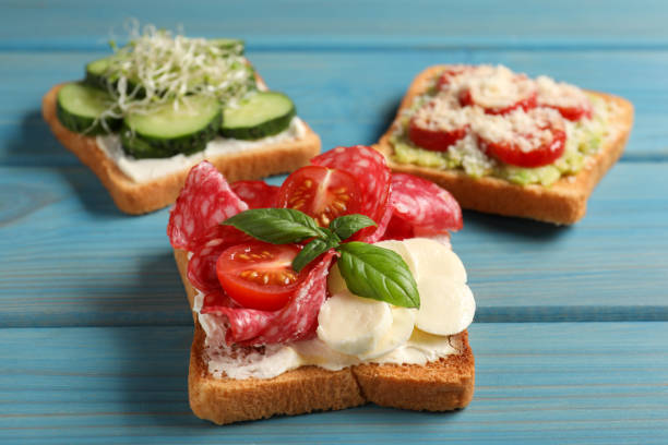 istock Tasty toasts with different toppings on light blue wooden table, closeup 1488464902