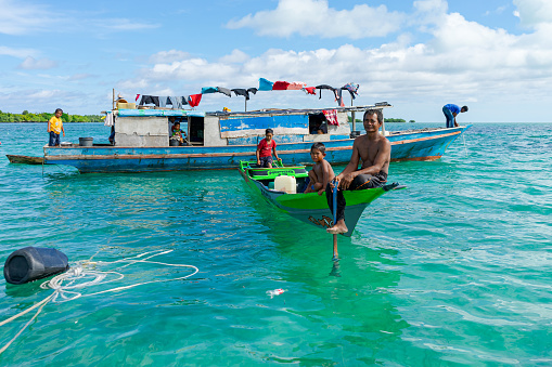 Omadal, Semporna Malaysia-Nov 19, 2021: A nomadic fishing family of the Bajau Laut ethnic taking a break on their small boat. Their larger boat serves as their family's living quarters.