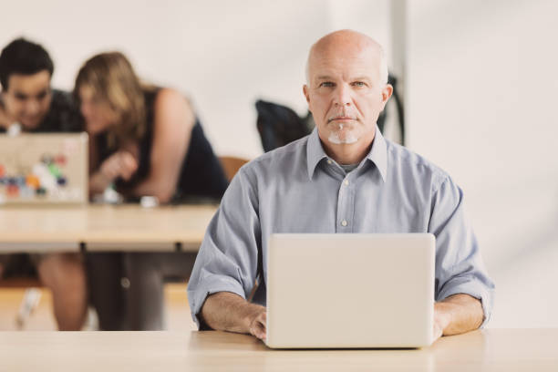 istock Mature man with laptop in library 1488466875
