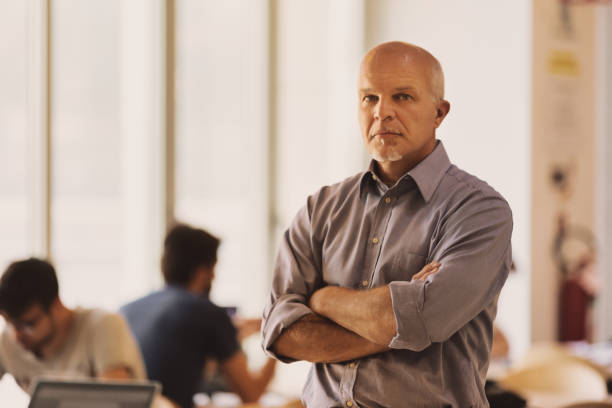 istock Elderly man with folded arms among people studying 1488466996