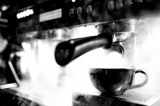 Cup of espresso being poured from a domestic espresso machine. Shallow depth of field.