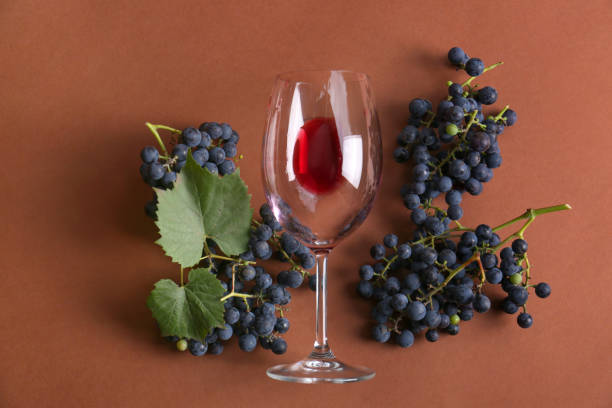 istock Overturned glass with red wine and grapes on brown background, flat lay 1488468541