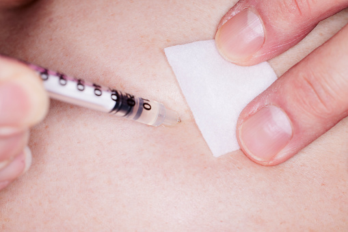 Close up of preparing to remove needle and syringe filled with Testosterone injected in the abdomen
