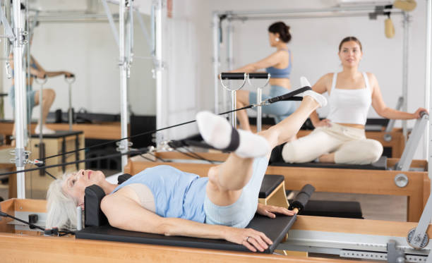 istock Senior woman doing stretching exercises on pilates reformer 1488474737