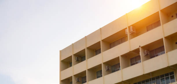 istock side view of yellow concrete building Intersect the orange sun. 1488475768