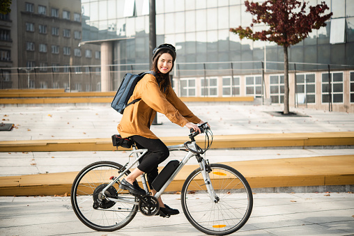 Asian businesswoman going to work on an electric bicycle