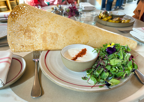 Indian dish with crunchy dosa bread on a restaurant table