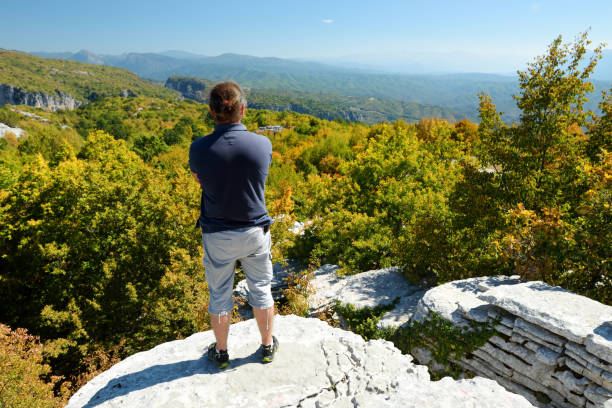istock Male tourist exploring Stone forest, natural rock formation, created by multiple layers of stone, located near Monodendri village in Zagori region, Northern Greece. 1488488867