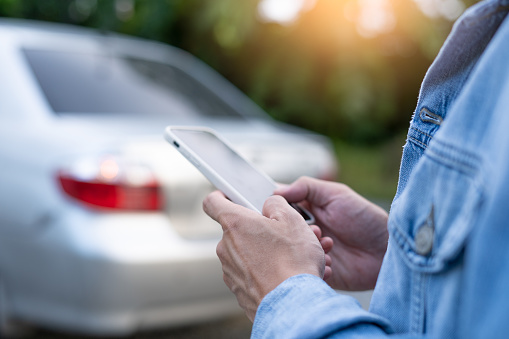 emergency safety. man is dialing a cell phone for an emergency number due to a car breakdown in the forest. Maintenance of the car before the trip increases safety from accidents.