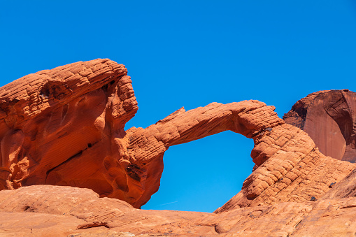 A closeup view of Delicate Arch, with snow-covered La Sal Mountains towering in background, on a clear sunny Winter day. Arches National Park, Utah, USA.