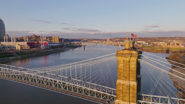 Approaching Push Shot of the Bennington 76 flag and Commonwealth of Kentucky Flag Flying on the John A. Roebling Bridge with Downtown Cincinnati Along the Ohio River