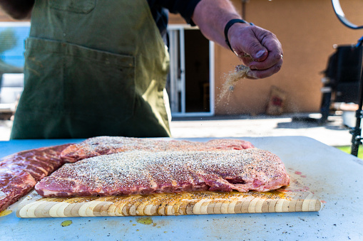 The raw rack of ribs is seasoned with a dry rub and left to marinate for several hours. Then it's slow-cooked on a charcoal grill until tender and smoky, ready to be devoured.
