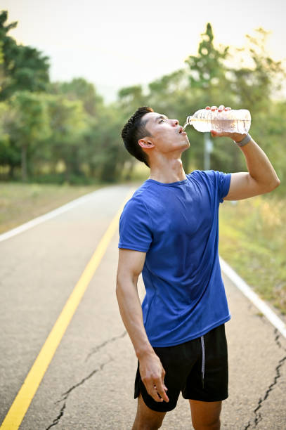 istock Thirsty and exhausted male runner drinks water from a bottle while running in a park 1488503161