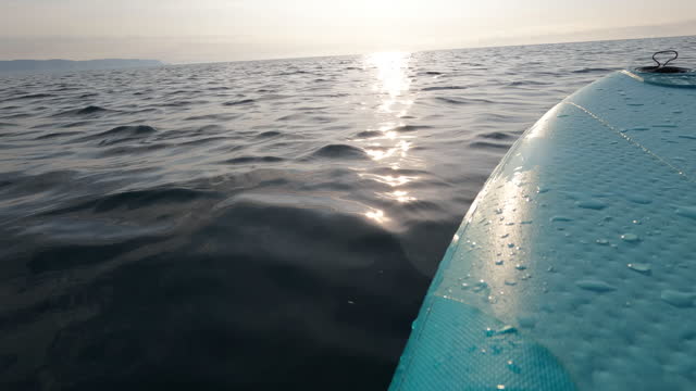 First person perspective of young woman stand up paddle boarding