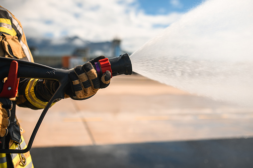 Firefighter spraying water with a fire extinguisher at the airport runway. Airport fire department at its finest.