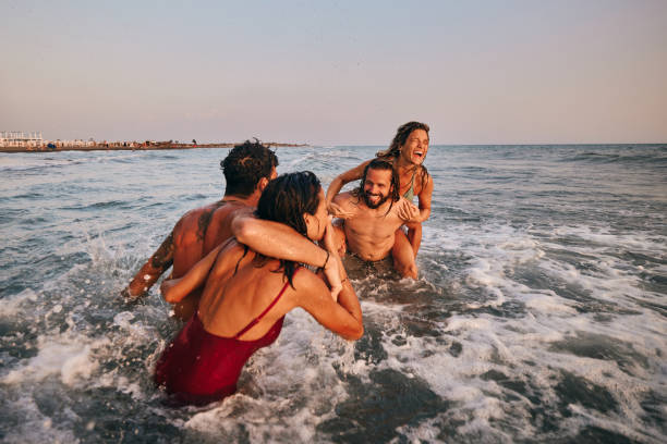 Amici spensierati che si divertono giocando durante le giornate estive in mare. - foto stock