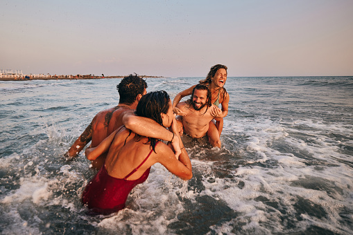 Young cheerful couples having fun during summer vacation in sea. Copy space.