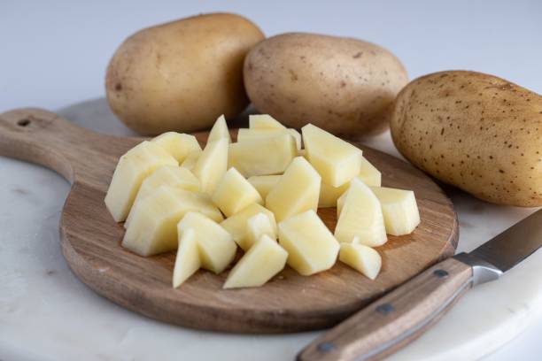istock Wooden cutting board with several peeled and sliced potatoes placed atop it. 1488514003
