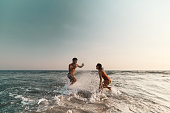 Cheerful couple having fun while splashing each other at sea.