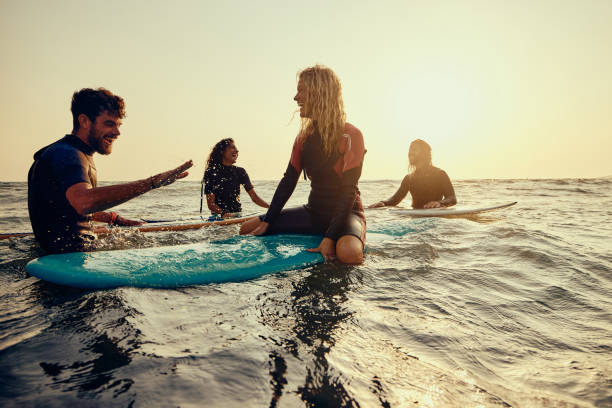 istock Cheerful surfers having fun while talking in sea at sunset. 1488515504