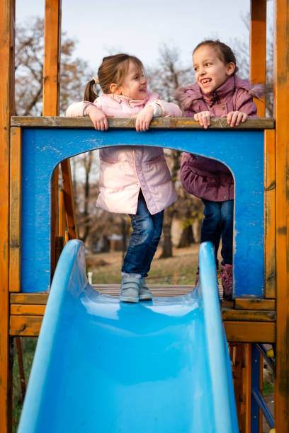 istock Two happy sisters having fun while playing whit slide at playground 1488515584