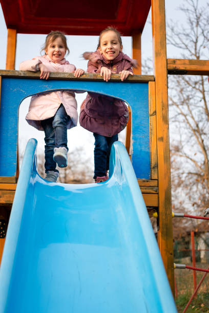 istock Two happy sisters having fun while playing whit slide at playground 1488515608