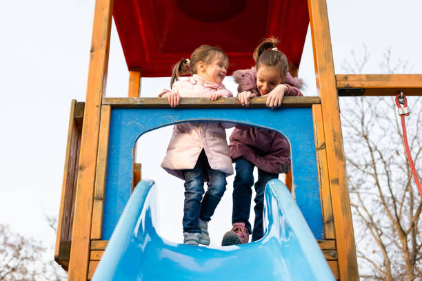 istock Two happy sisters having fun while playing whit slide at playground 1488515684