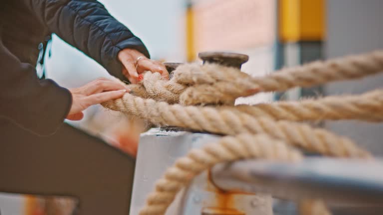 Handheld shot of passengers holding rope while embarking in boat. Men and women are traveling during vacation. They are spending leisure time.