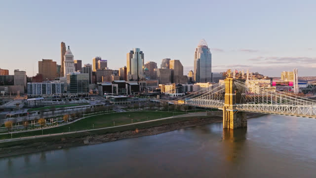 High Angle Push-In View  of the John A. Roebling Suspension Bridge into Downtown Cincinnati Along the Ohio River at Sunset
