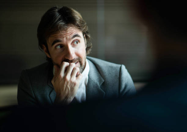 worried male entrepreneur on a meeting in the office. - nail biting imagens e fotografias de stock