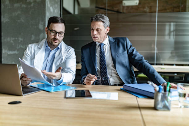 istock Young doctor and businessman working on reports at doctor's office. 1488516838