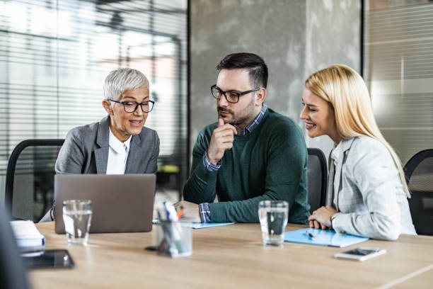 istock Senior agent using computer with young couple in the office. 1488516950