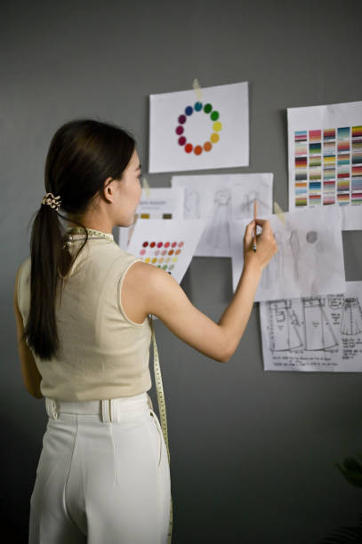 istock Confident female fashion designer checking her model sketches and working in her studio. 1488519026