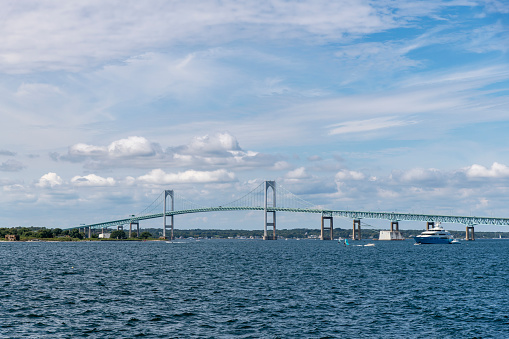 View over the water of Mount Hope Bay towards two-lane suspension Mount Hope Bridge in Rhode Island, USA connecting Portsmouth and Bristol over Route 114