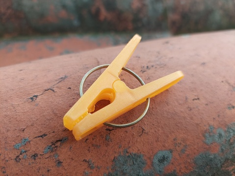 An orange plastic clothespin on a rooftile