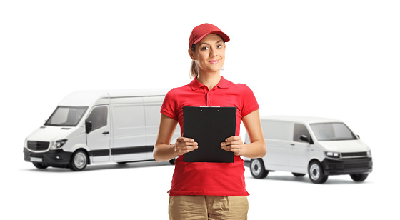 Delivery woman holding a document in front of transport vans isolated on white background
