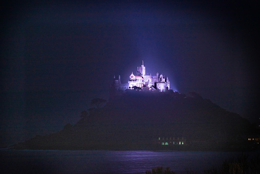 St Michael's Mount, Cornwall, England . Taken from Marazion at night. Once a week the castle is illuminated with purple light.