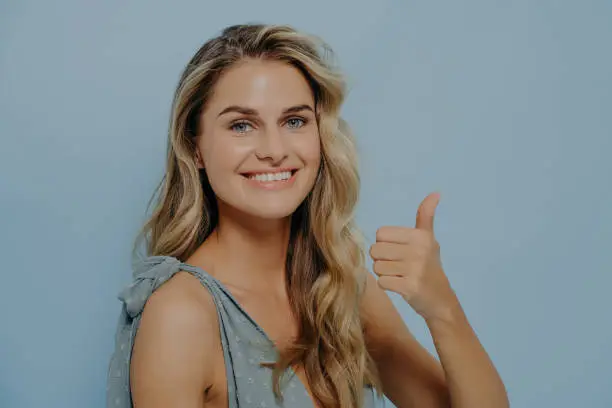 Photo of Cheerful blonde woman showing thumbs up gesture