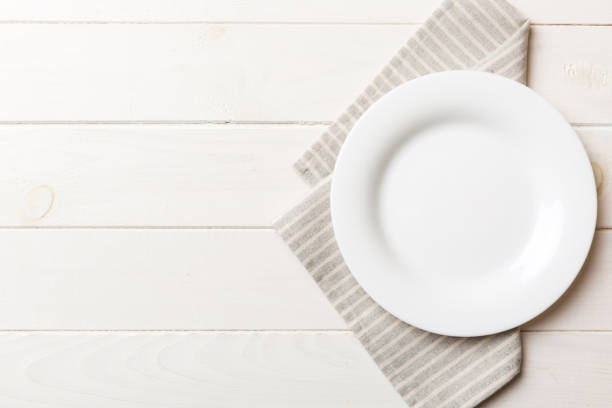 istock Top view on colored background empty round white plate on tablecloth for food. Empty dish on napkin with space for your design 1488532794