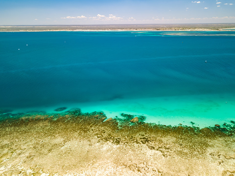 Bird's eye view of the turquoise waters surrounding the island of Nosy Ve in Madagascar. The crystal-clear water is visible, creating a beautiful contrast with the dark of the underwater reefs