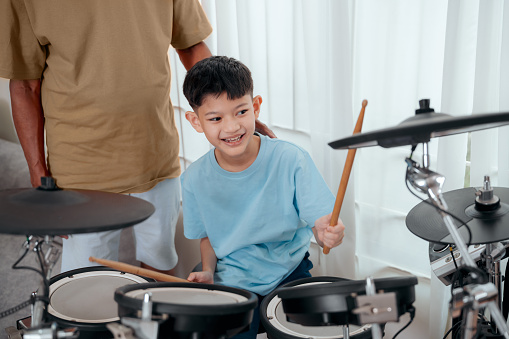 Asian Grandfather teaching grandson playing drum in the living room at home